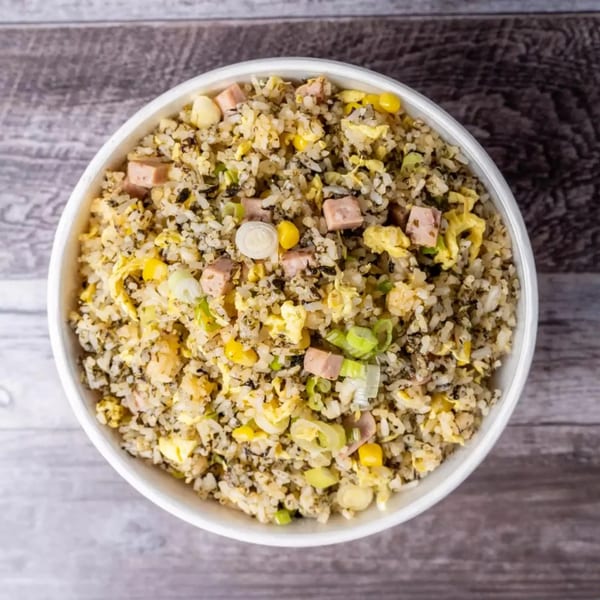 Top-down view of a white bowl filled with fried rice, spam, corn, and green onions.