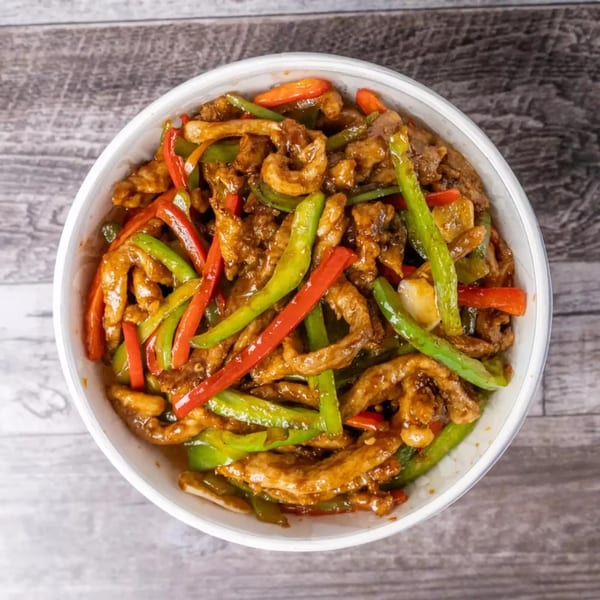 Top-down view of a white bowl filled with stir-fried beef, green beans, and red bell peppers.
