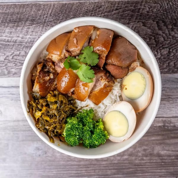 Braised pork belly with rice, pickled mustard greens, broccoli, and hard-boiled eggs in a white bowl.